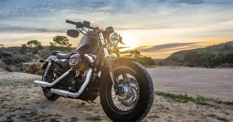 Black motorcycle parked on a dirt road at sunset in a rocky desert landscape