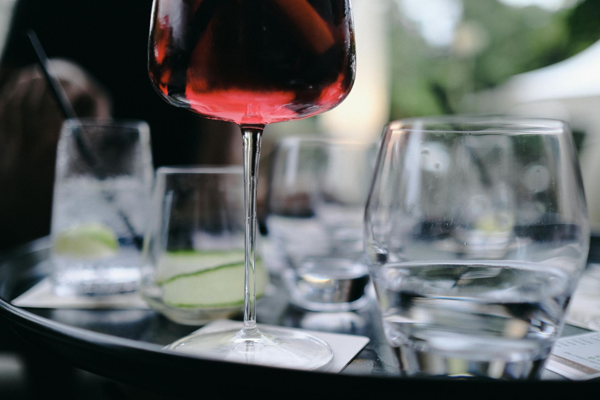 Wine glasses on a table, with a red wine glass in the foreground and blurred dinner setting behind