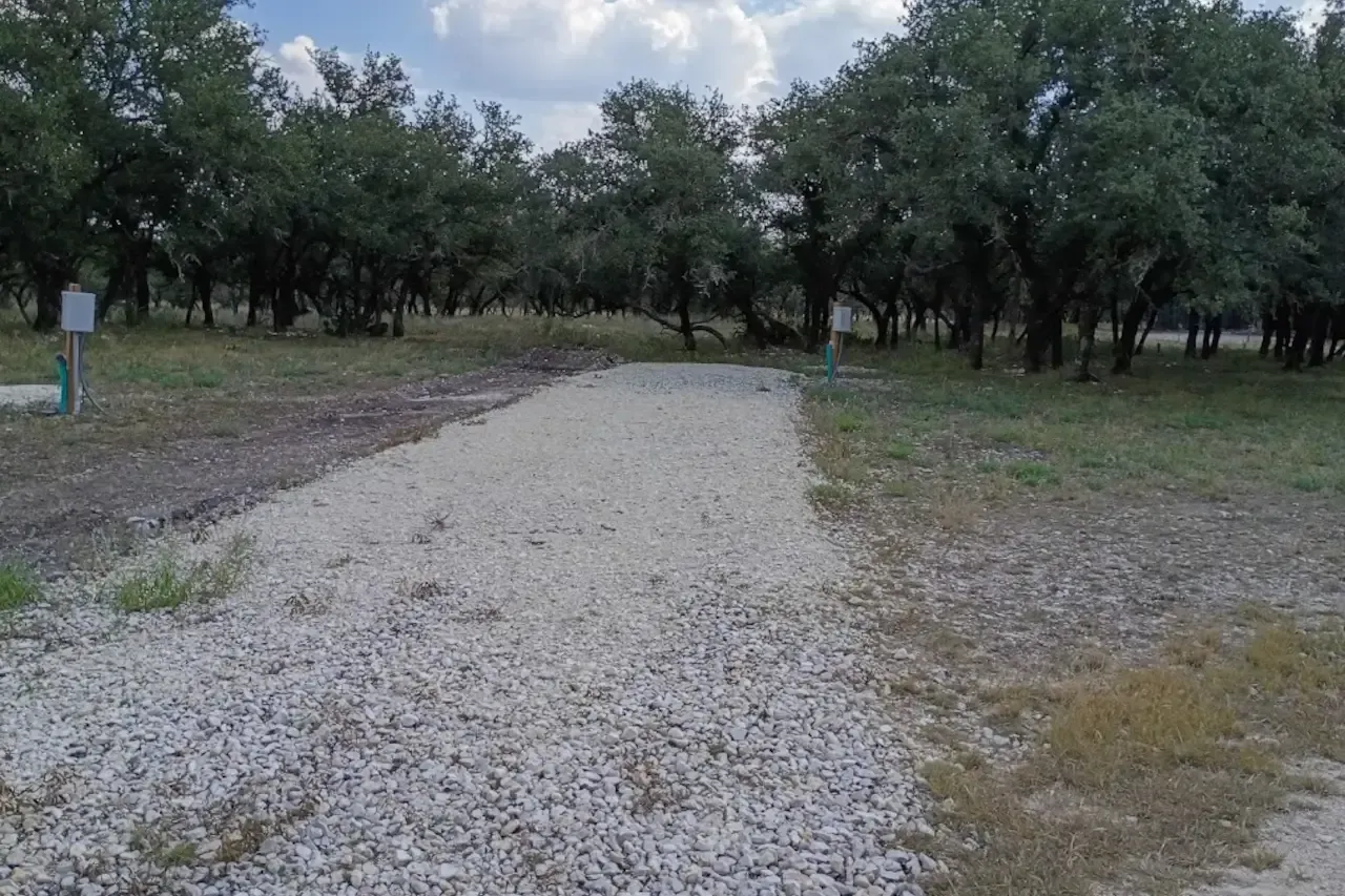 Gravel path through a wooded area under a cloudy sky
