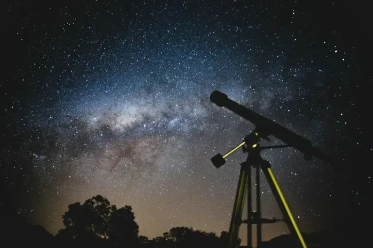 Telescope on a tripod silhouetted against a starry Milky Way night sky