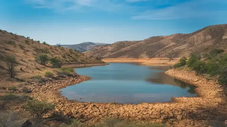 Dry lake surrounded by rocky hills under a clear blue sky