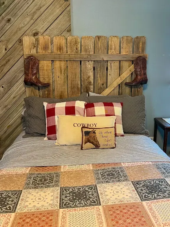 Rustic bedroom with patchwork quilt, plaid pillows, and a wood headboard against a wood-plank wall