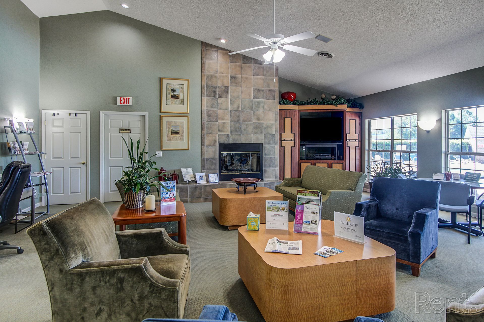 Meridian Park Clubhouse- view of chairs, tables, work center, fireplace, door toward hallway in fitness center and bathroom. 