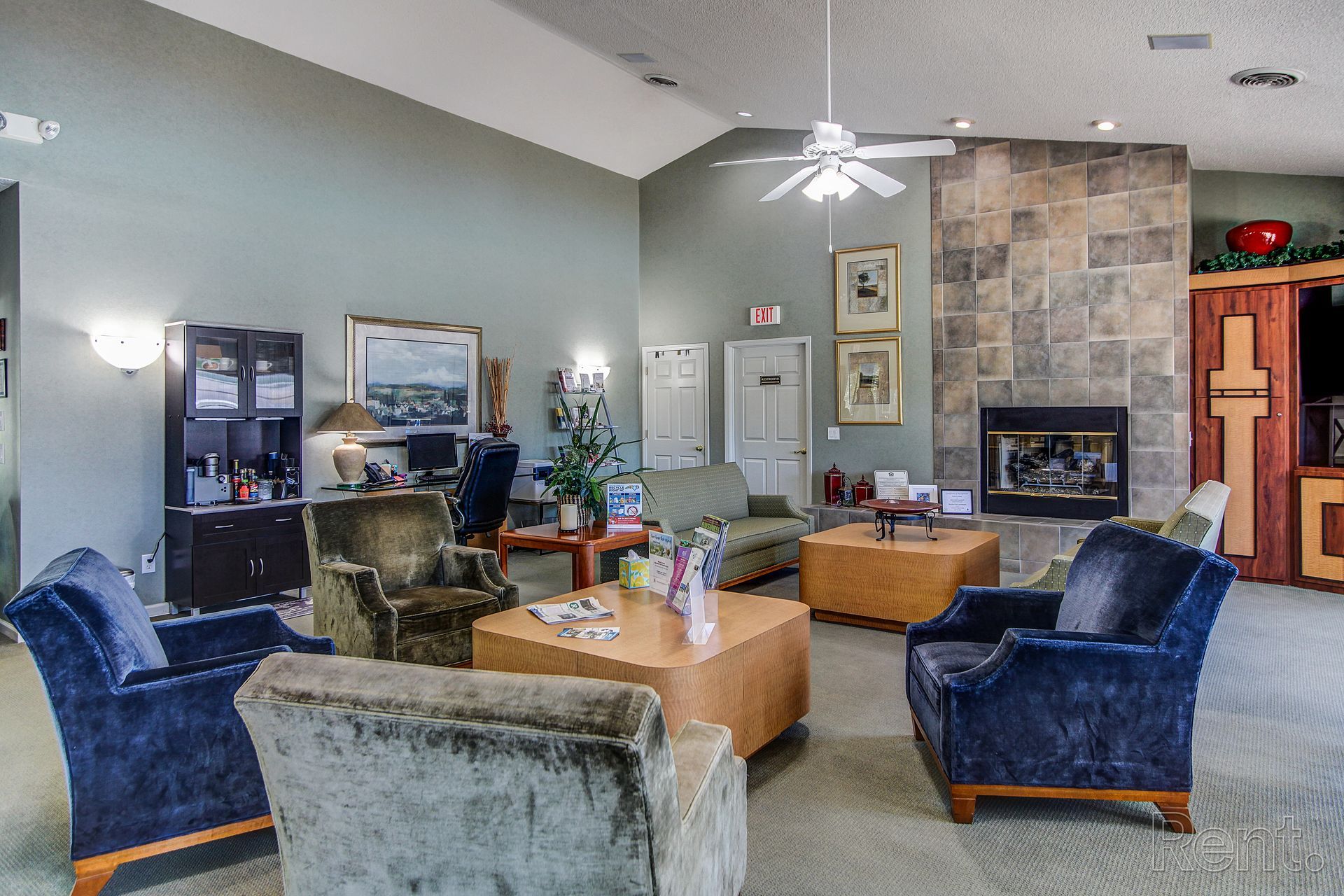 Meridian Park Clubhouse- view of chairs, tables, work center, fireplace, door toward hallway in fitness center and bathroom. 