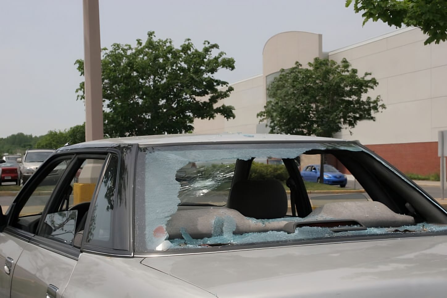 a car with a broken windshield is parked in front of a building
