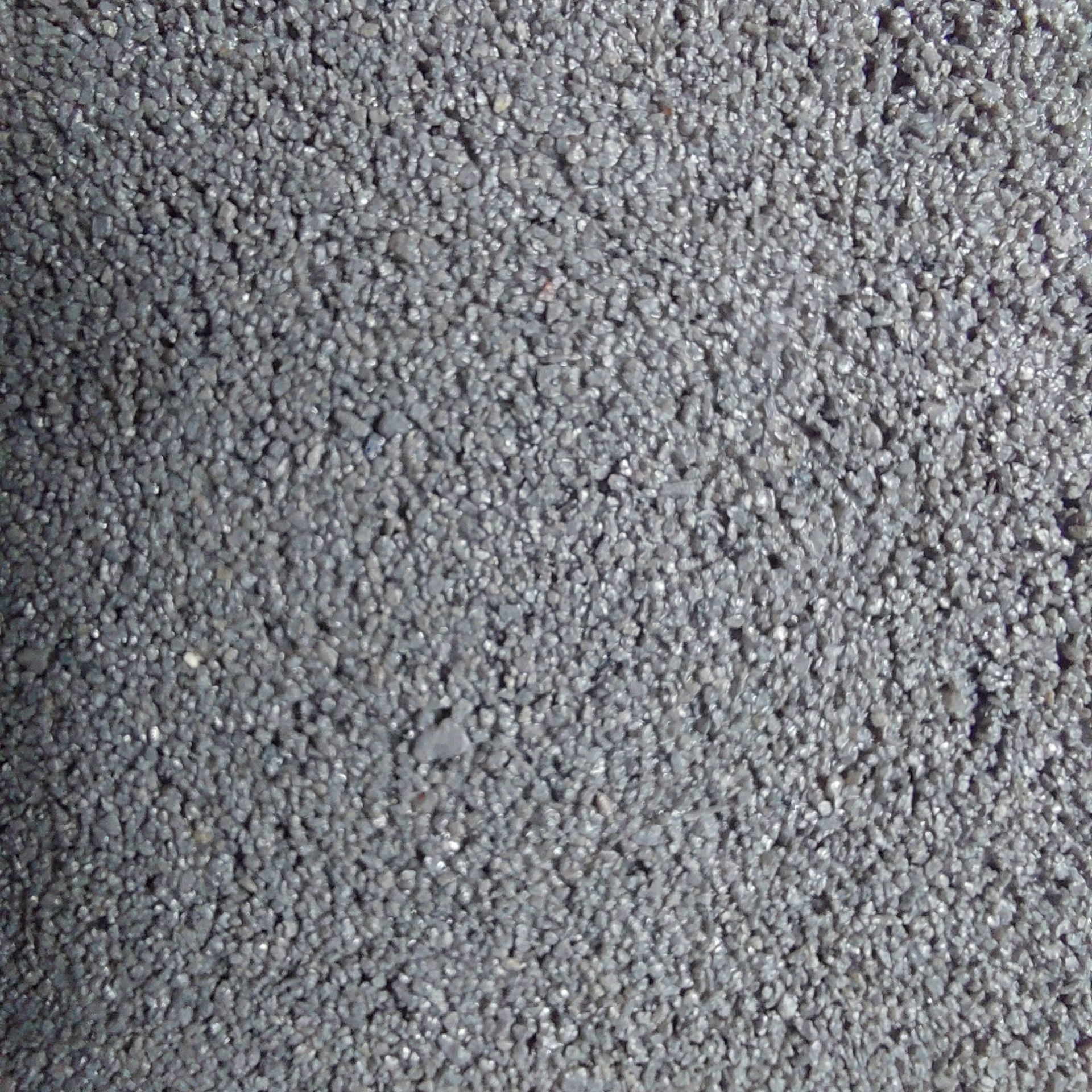 Close-up of dark asphalt surface, textured with small, granular stones.