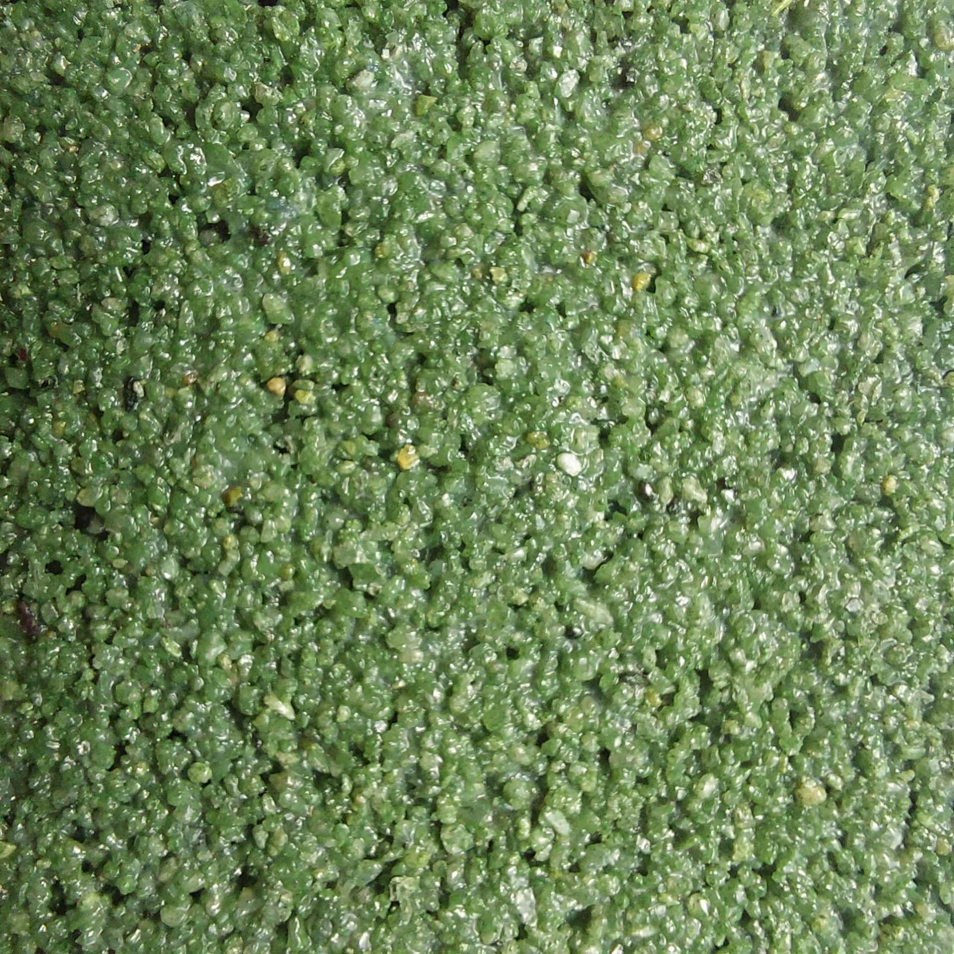 Close-up of a green, textured surface composed of small, irregular granules, possibly aggregate.