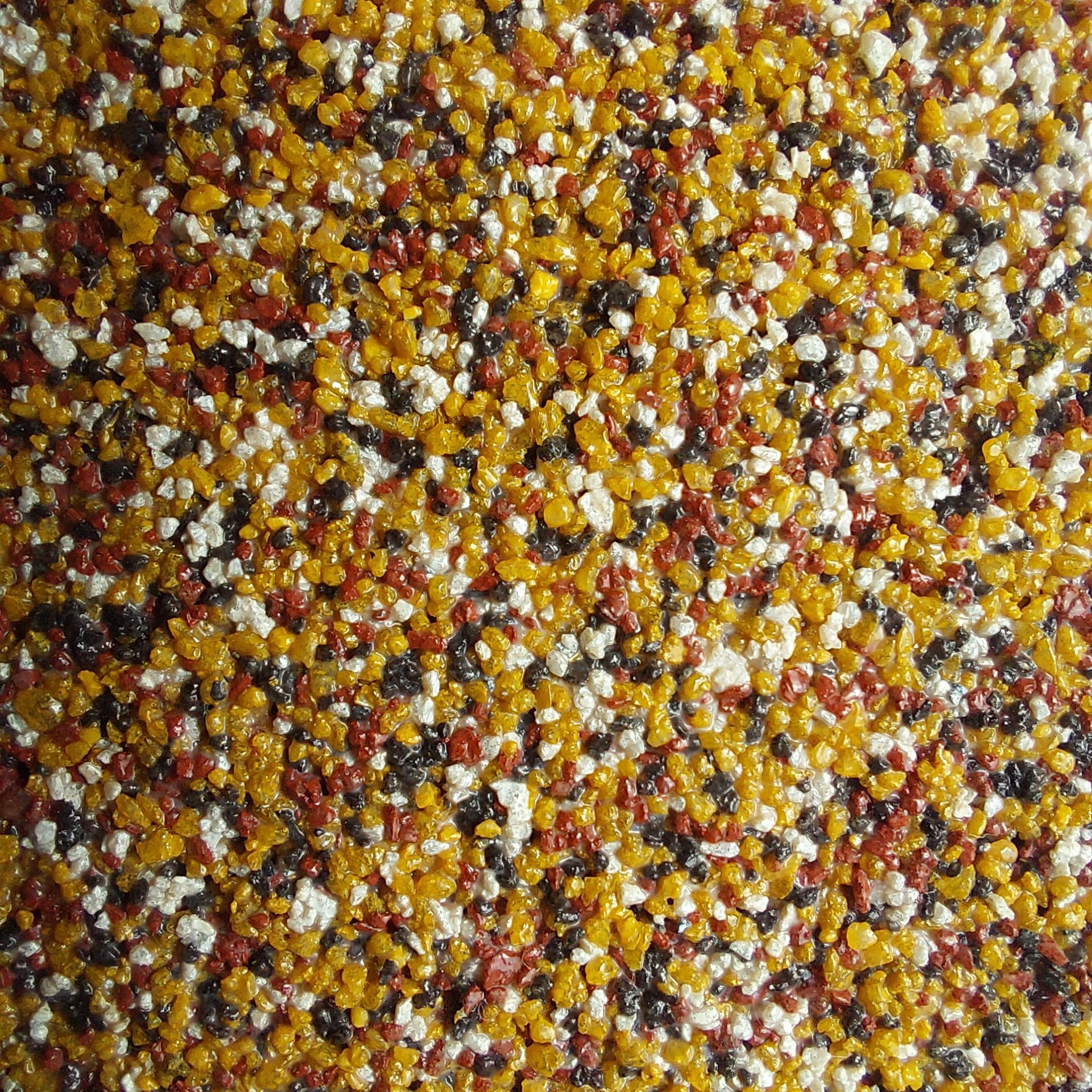 Close-up of a speckled surface with gold, red, black, and white granules.