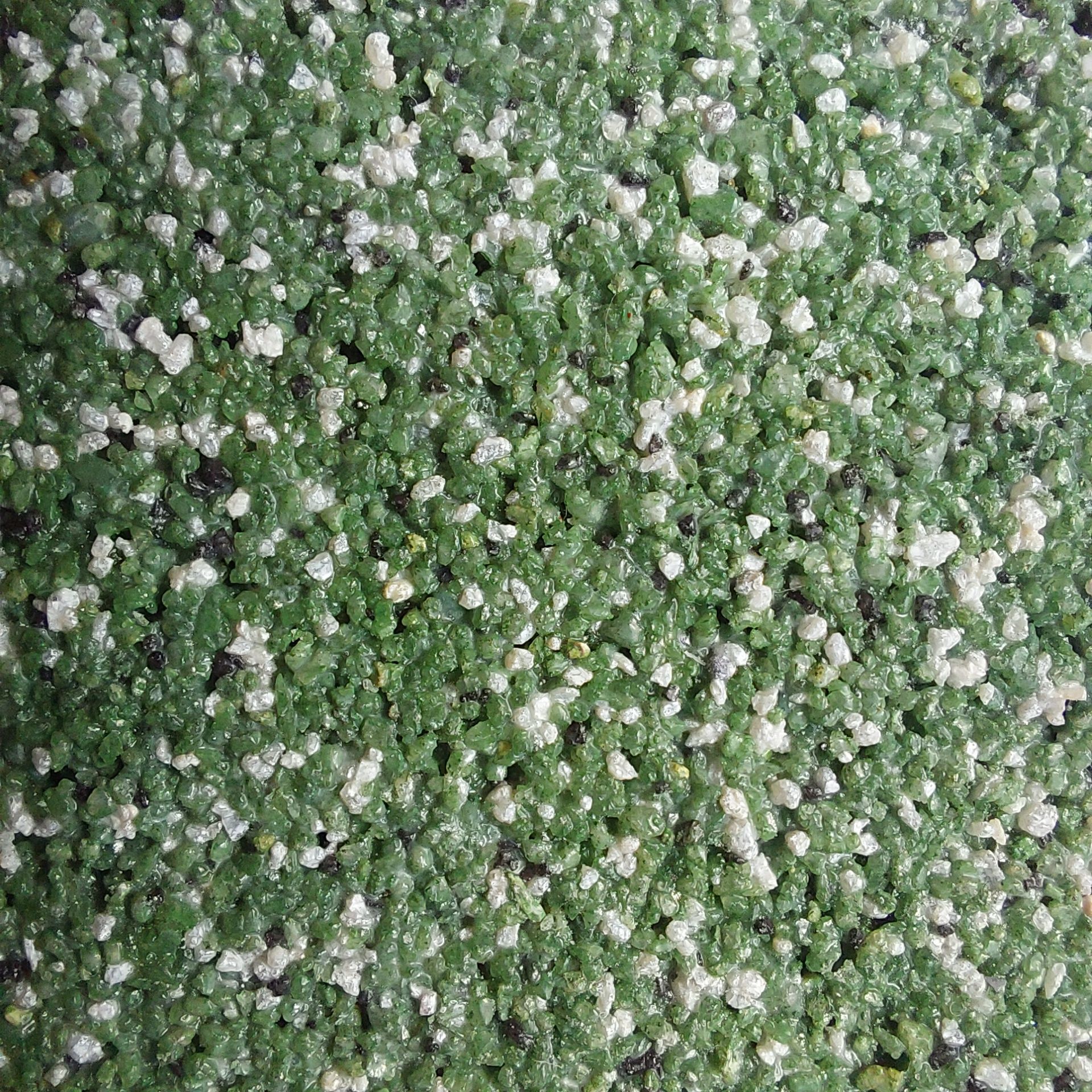 Close-up of a textured surface with green and white speckled pebbles.