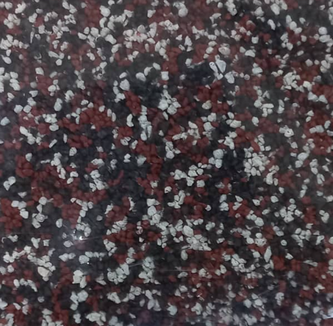 Close-up view of a surface with a speckled pattern of red, white, and black particles.
