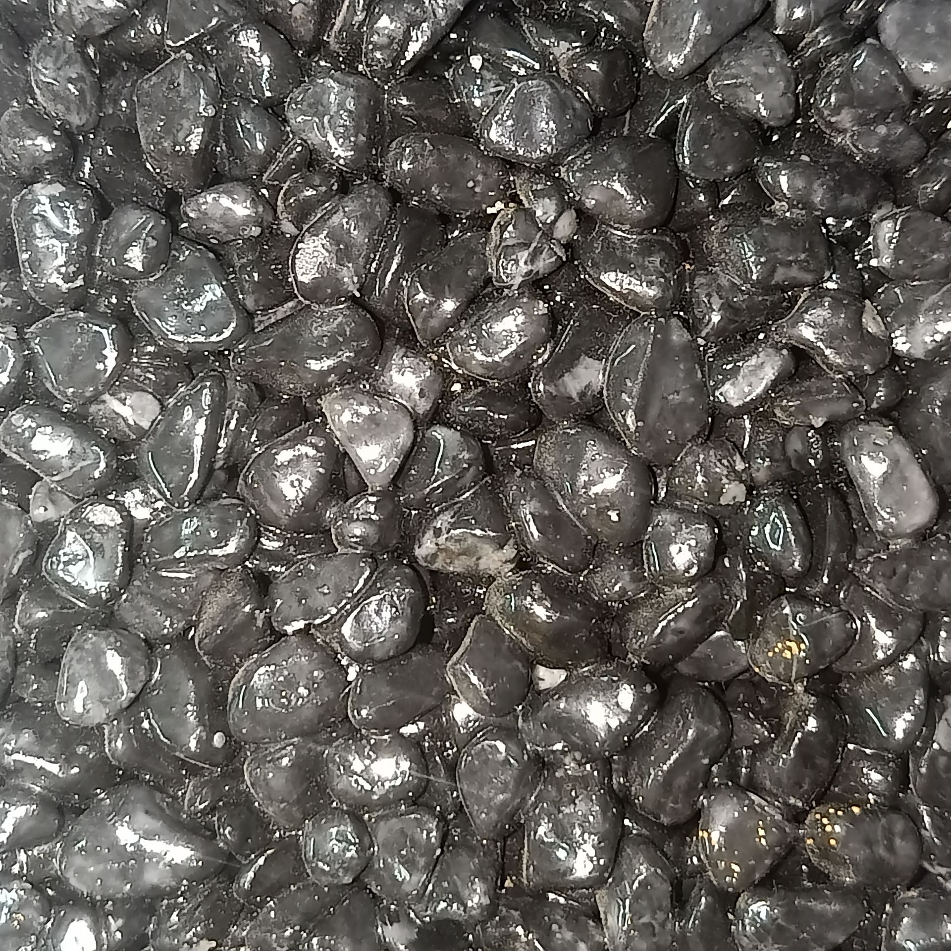 Shiny, dark gray, rounded pebbles.