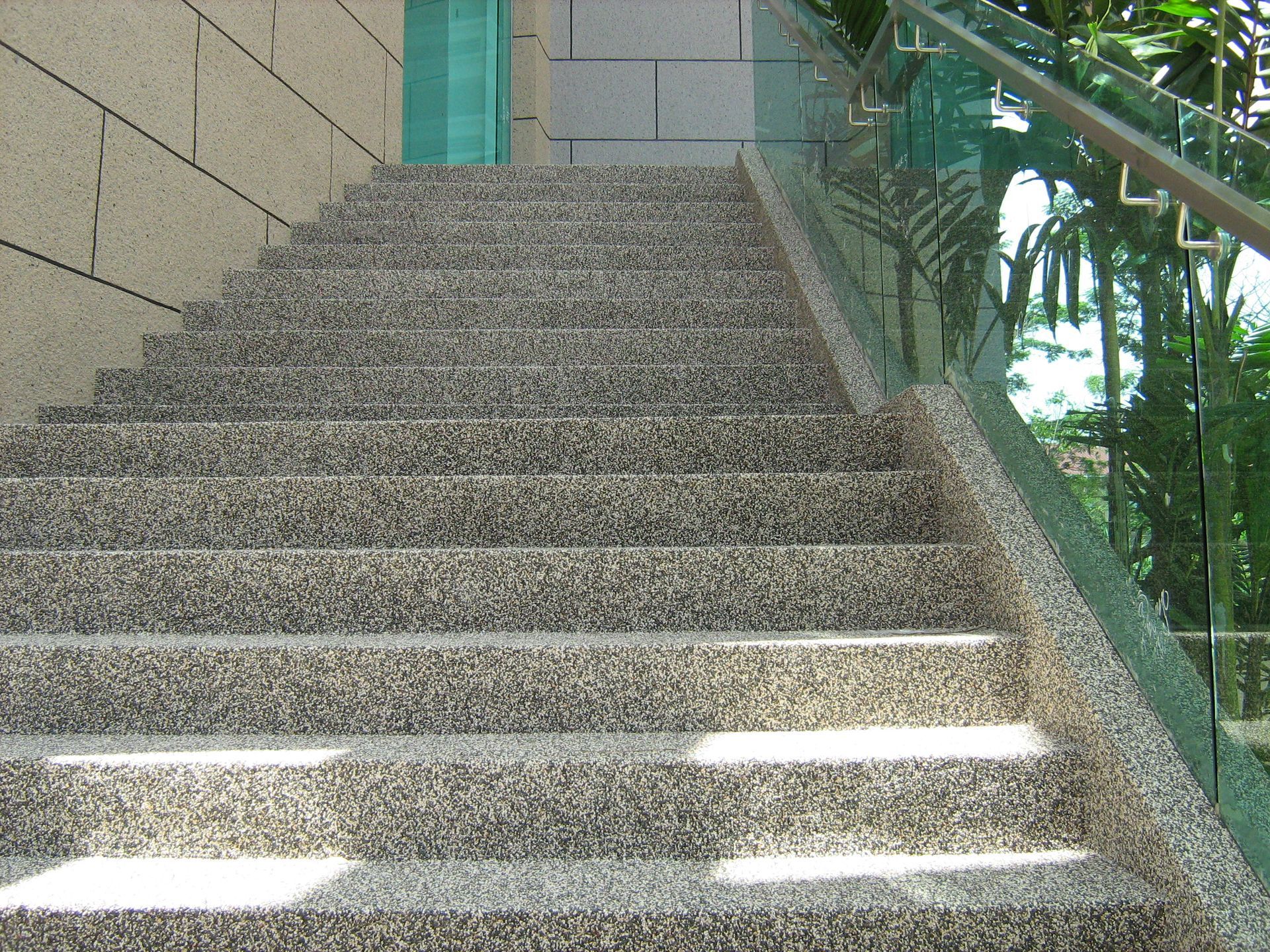 Stone steps leading upwards, with a glass and metal railing on the right.
