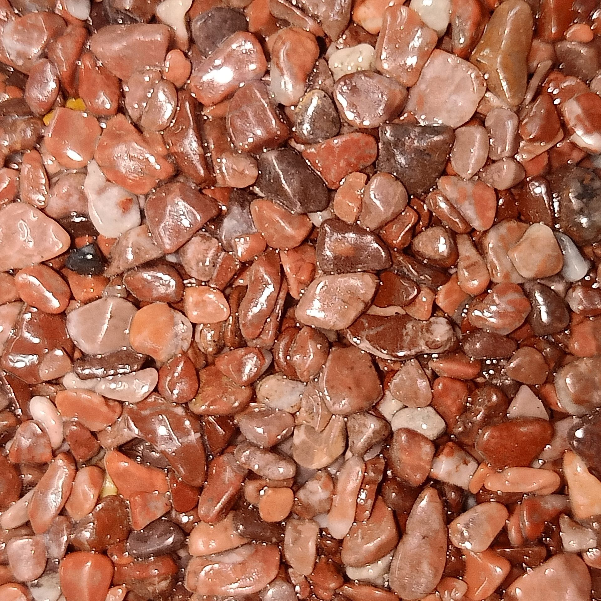 Close-up of small, reddish-brown pebbles, possibly used in landscaping or decorative applications.