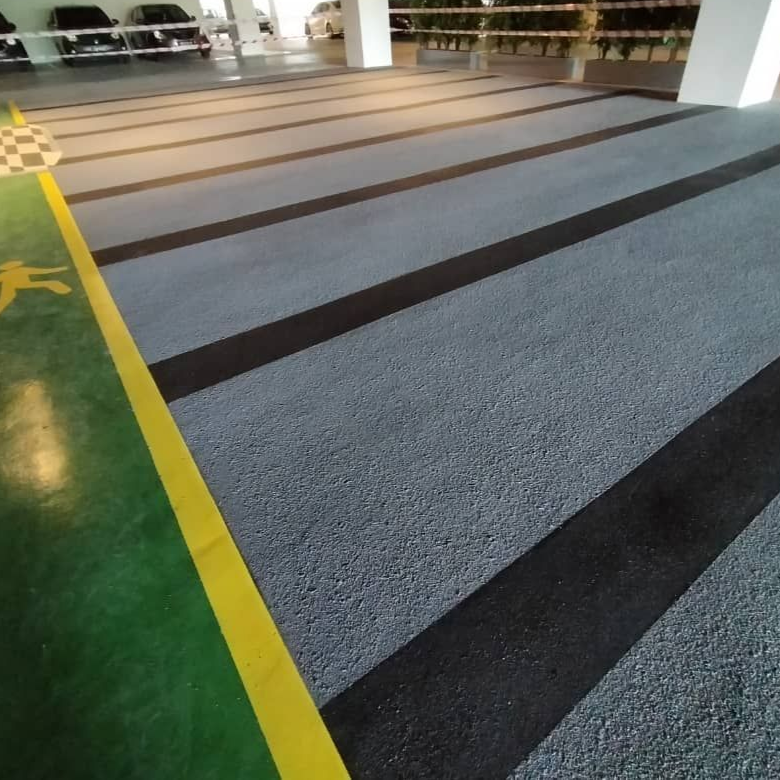 Gray parking garage floor with black stripes, and green section with yellow border.