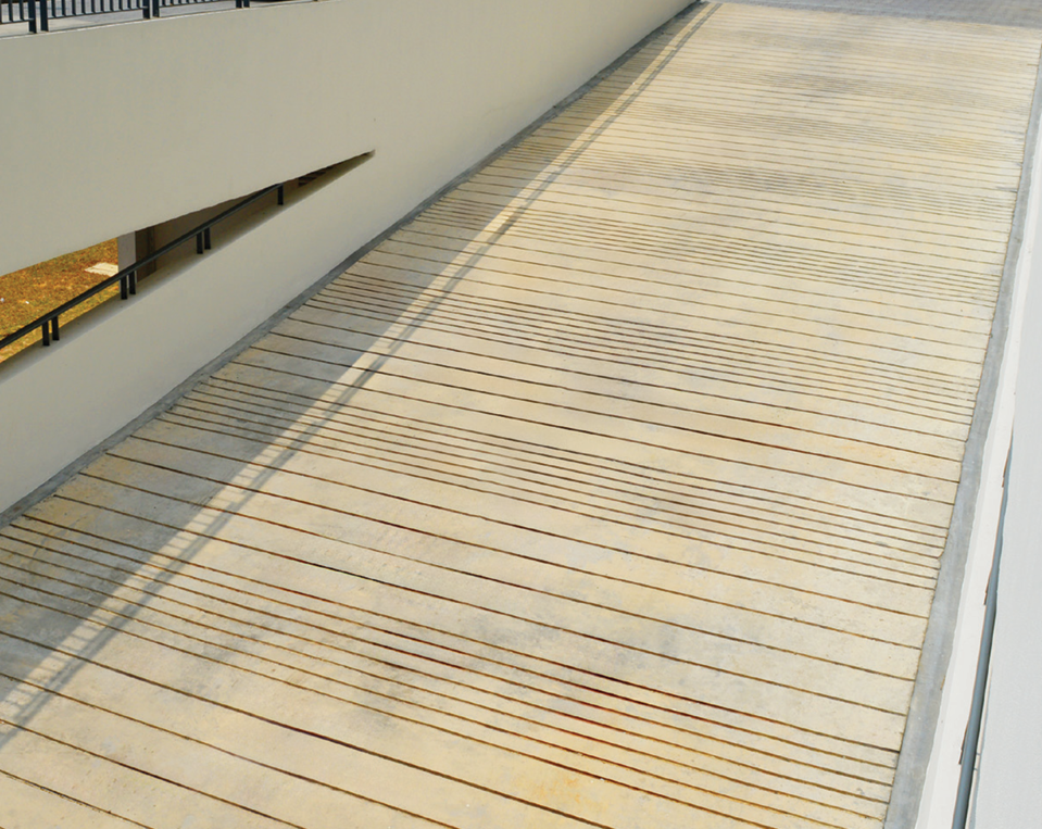 Concrete ramp leading down from a building with handrails, creating an accessible entry.