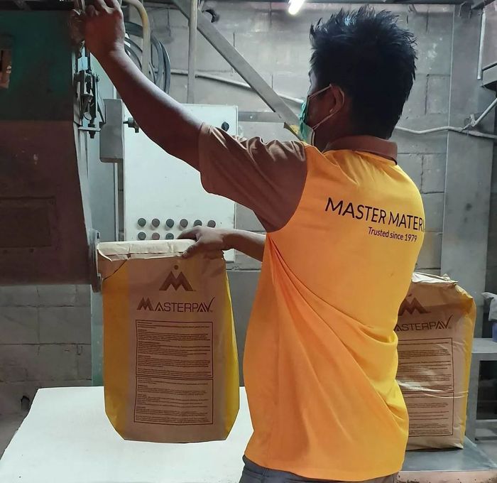 Man in a yellow shirt filling a bag with a product labeled