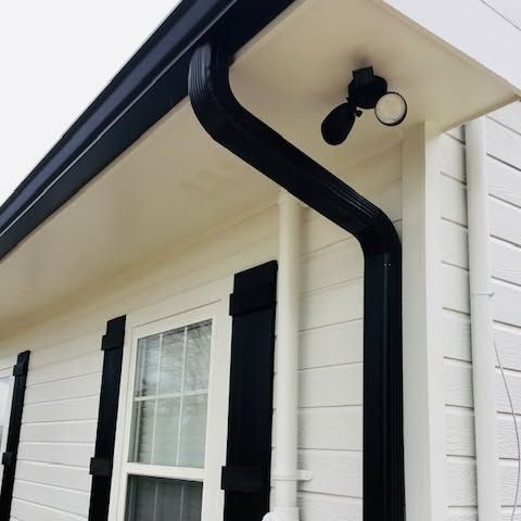 White house eave with black gutter and mounted security light above shuttered window