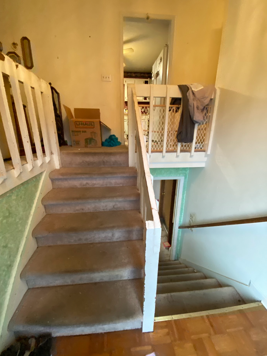 Indoor staircase with carpeted steps, white railings, and a landing in a beige hallway.