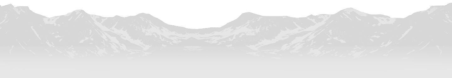 Snowy mountain range under a pale sky, with a faint silhouette of hills in the foreground