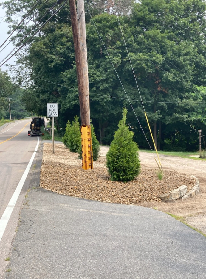 Roadside view with a speed limit sign, power pole, small trees, and a parked vehicle in the distance.