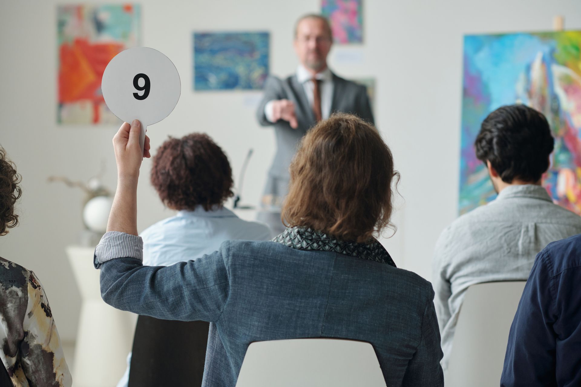 Man raises his number tablet in an auction house, showing Stevens Auction Service’s auctioneer servi