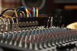 Close-up of an audio mixing console with colorful cables and knobs