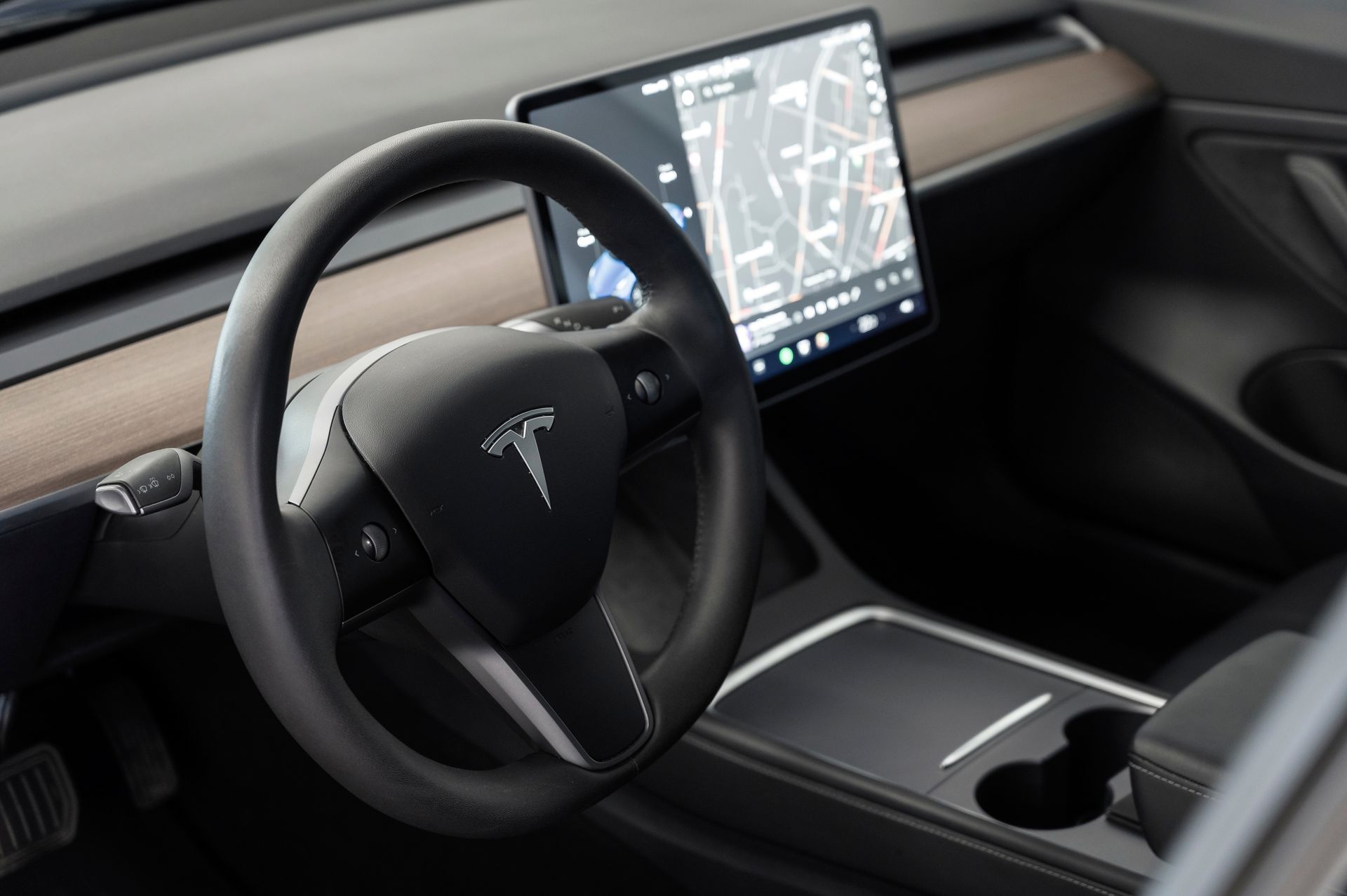 Interior of a Tesla car with a steering wheel and touchscreen display showing navigation.