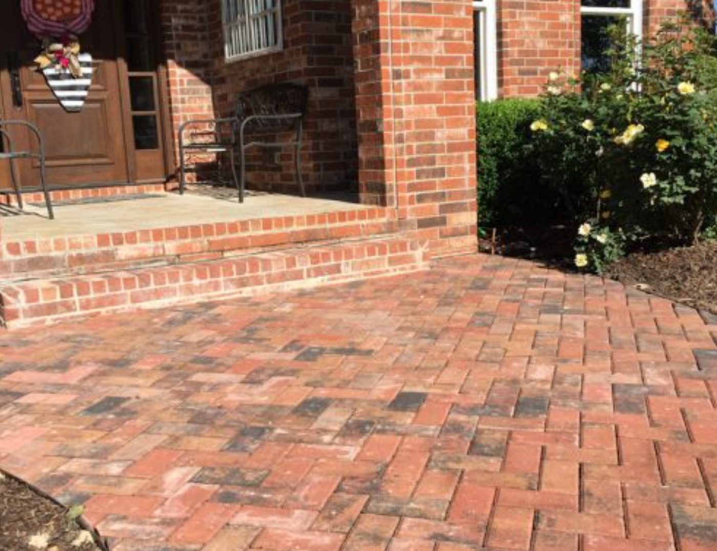 There is a brick walkway in front of a brick house.