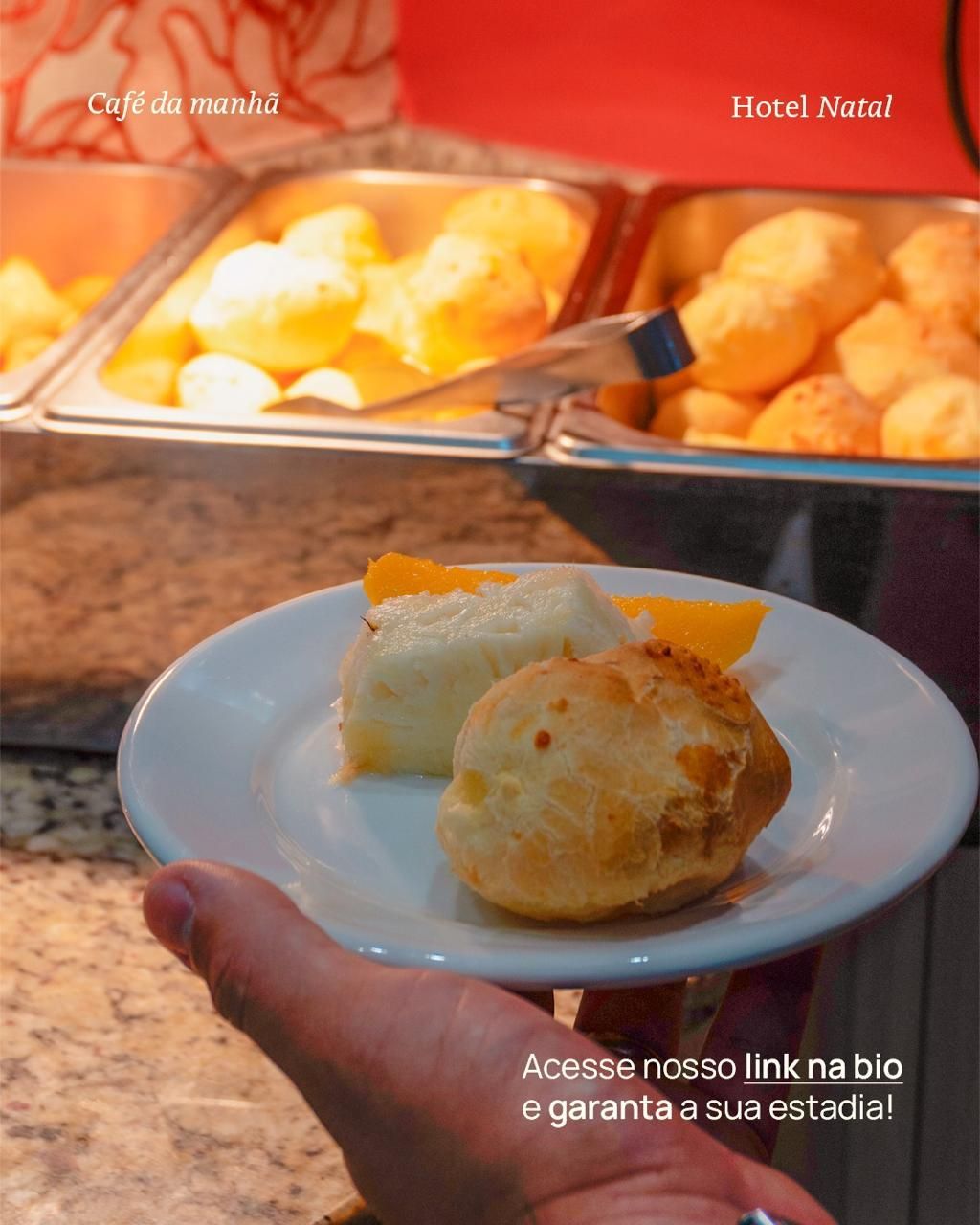Prato com uma fatia de bolo e pastelaria em frente a uma bandeja de buffet no Hotel Natal.