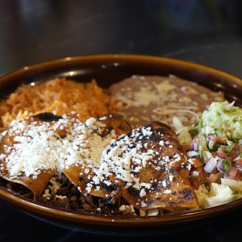 Taco plate with rice, beans, shredded cheese, and lettuce in a brown bowl