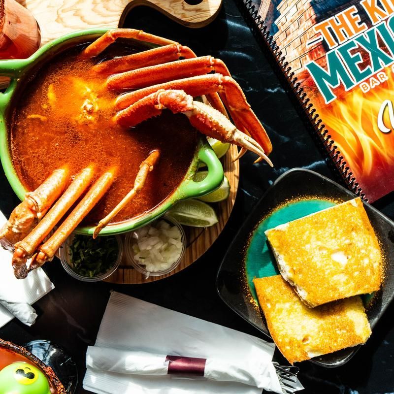 Assorted snacks and seafood on a table, including crab in sauce, crackers, and chips.