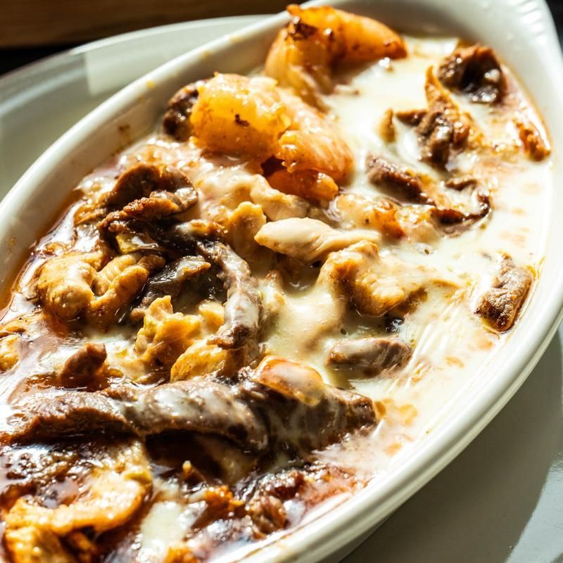 Creamy brown mushroom dish in a white oval bowl, topped with sauce and herbs