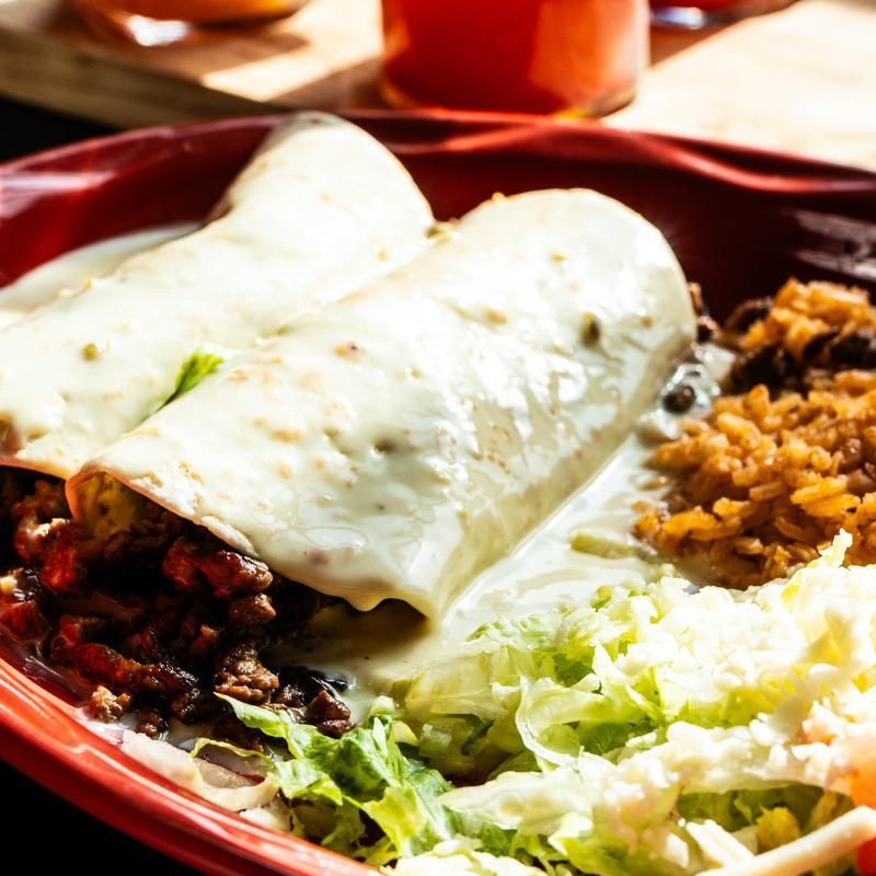 Close-up of a plate with folded white tortillas, rice, beans, lettuce, and salsa on a red tray