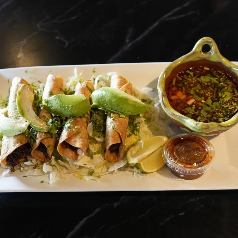 Plated fish tacos with lime wedges and sauces on a white platter