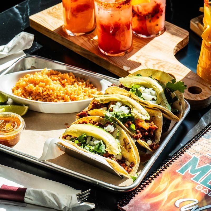 Tray of tacos with rice, chips, and drinks on a restaurant table