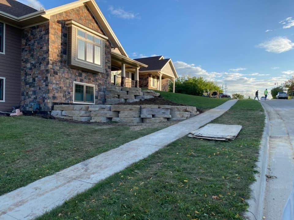 Stone houses along a sloped suburban sidewalk beside a quiet street at sunset