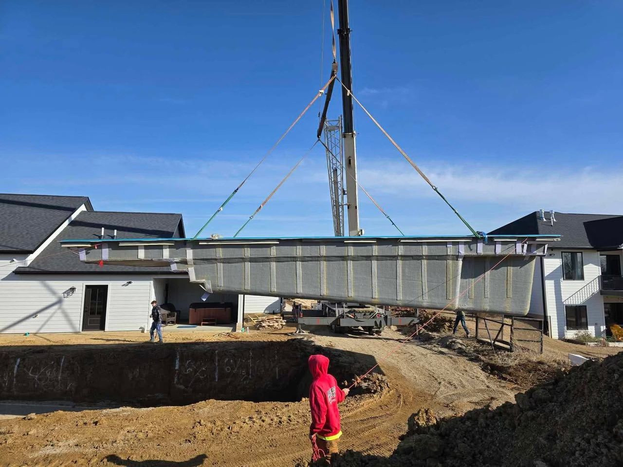 Construction site with a small child in a red coat near a trench under a clear blue sky