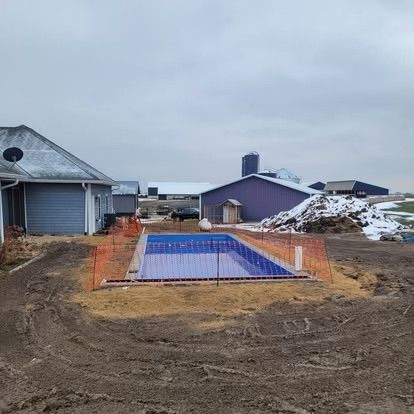 Backyard pool under construction, with a blue-lined rectangular pool pit and dirt piles around it
