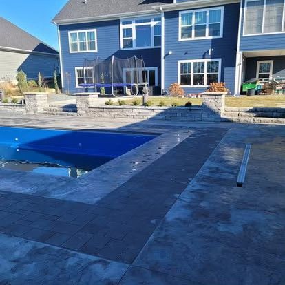 Backyard patio with a covered pool, stone walkway, and blue two-story house in the background