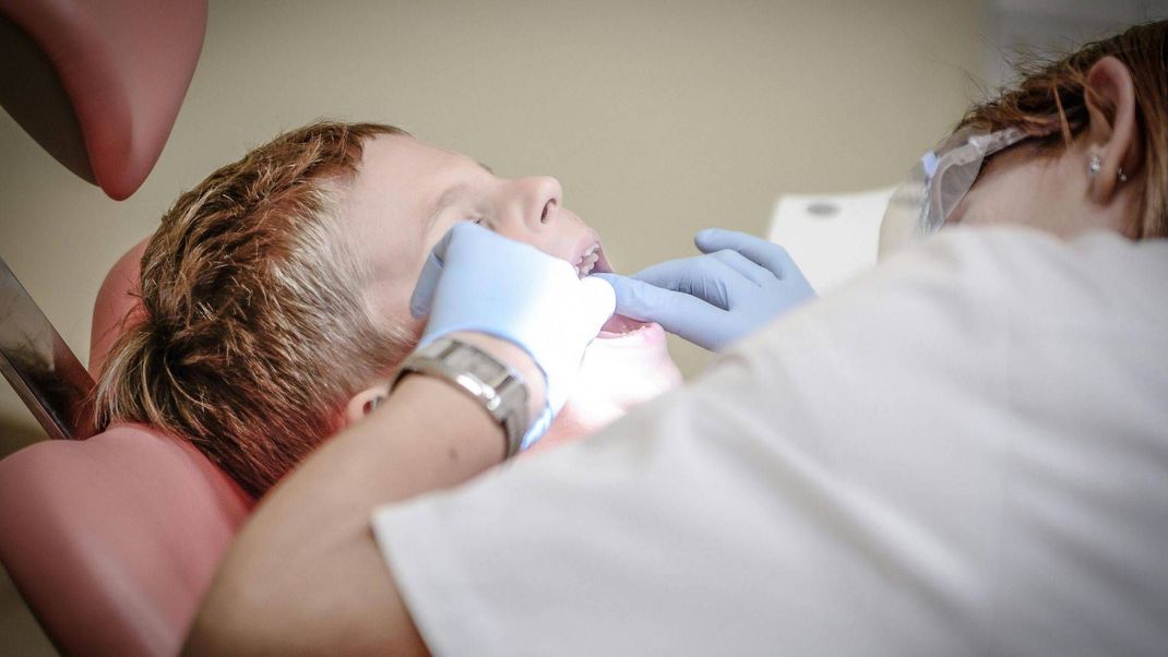 Un niño pequeño se hace examinar los dientes por un dentista.