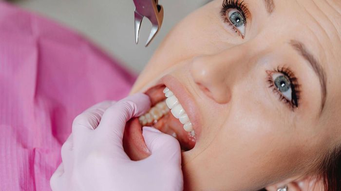 Una persona se está haciendo examinar los dientes por un dentista.