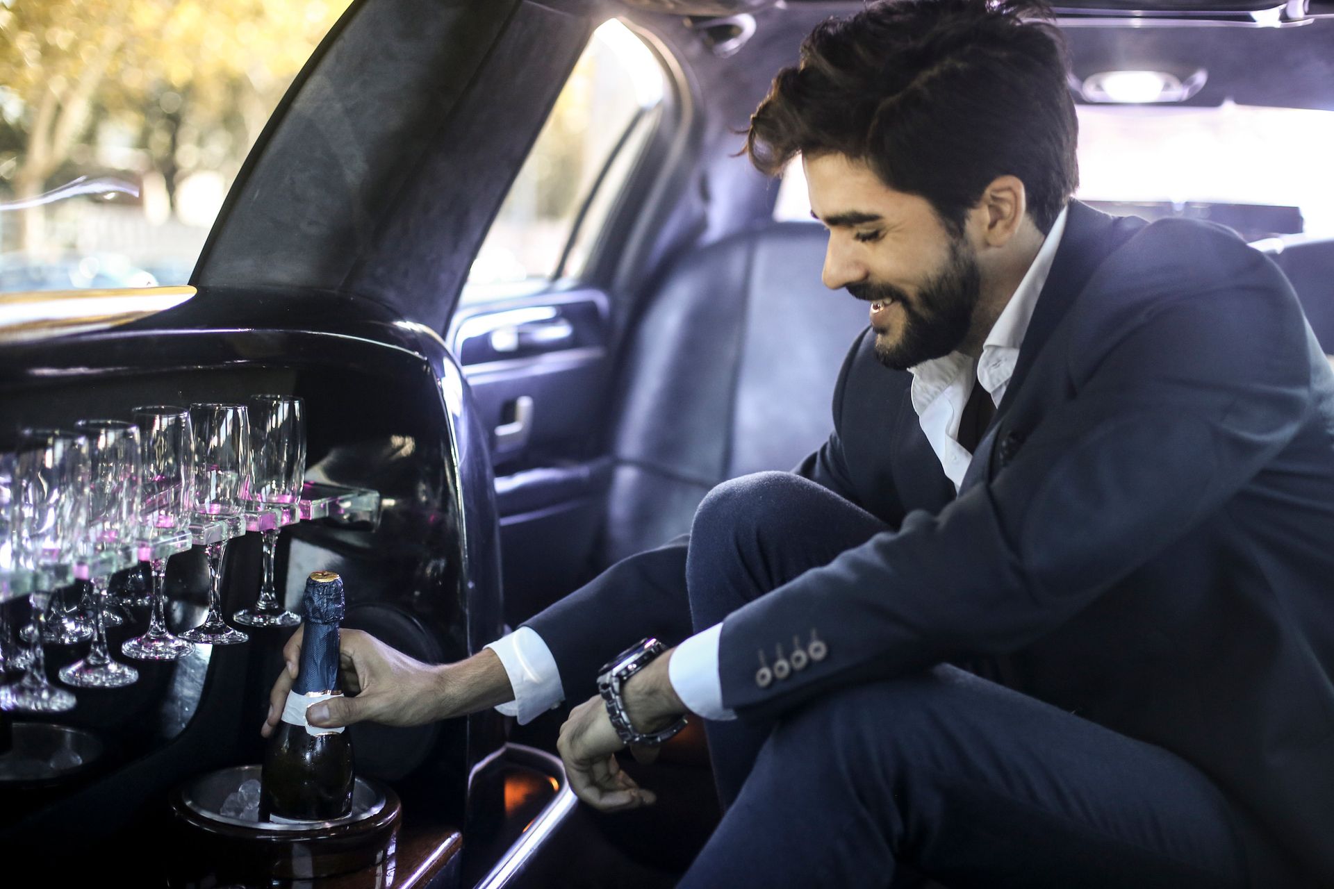 A man is sitting in a limousine holding a bottle of champagne. A man is sitting in a limousine holding a bottle of champagne.