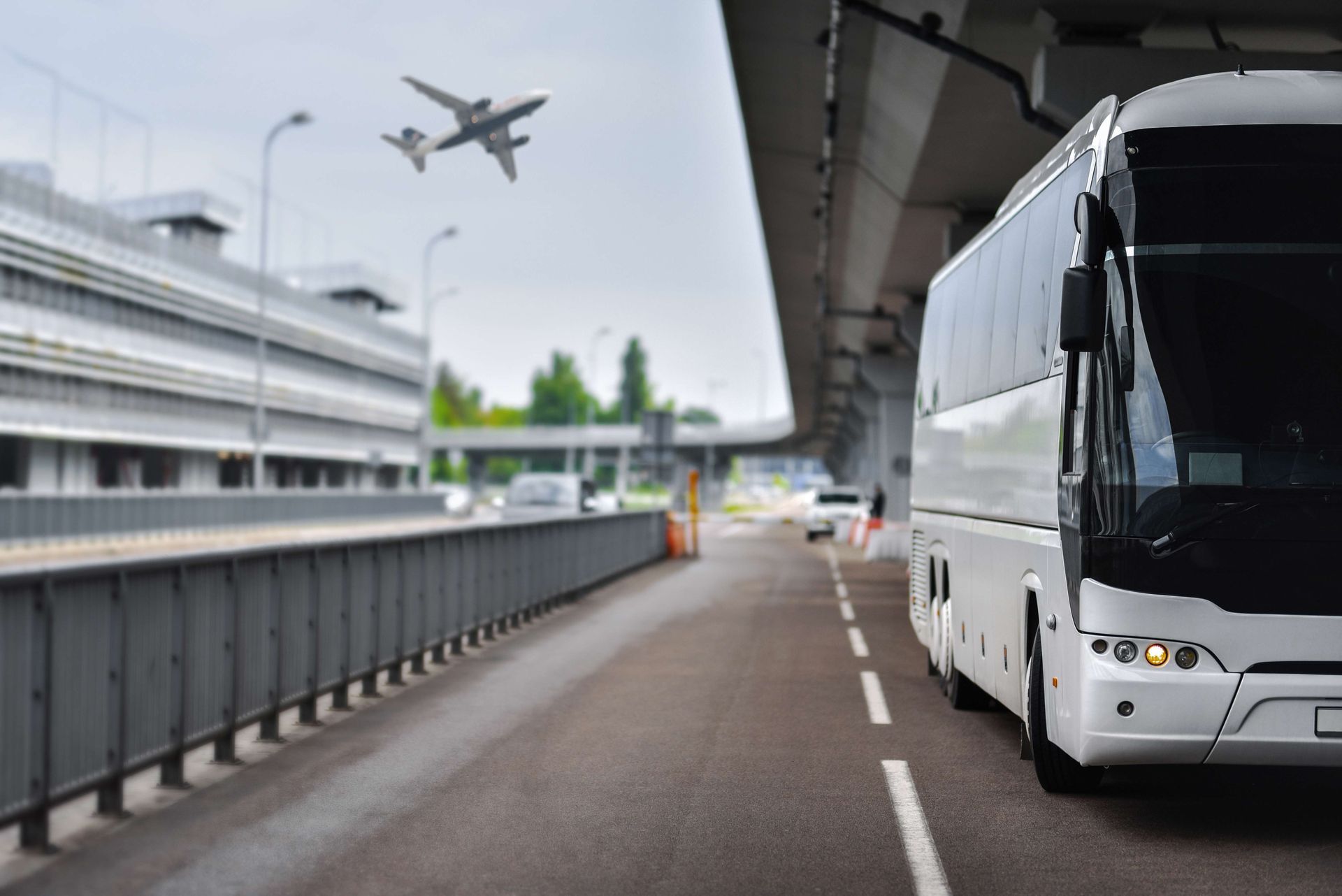 A white bus is driving down a road next to an airport. A white bus is driving down a road next to an airport.