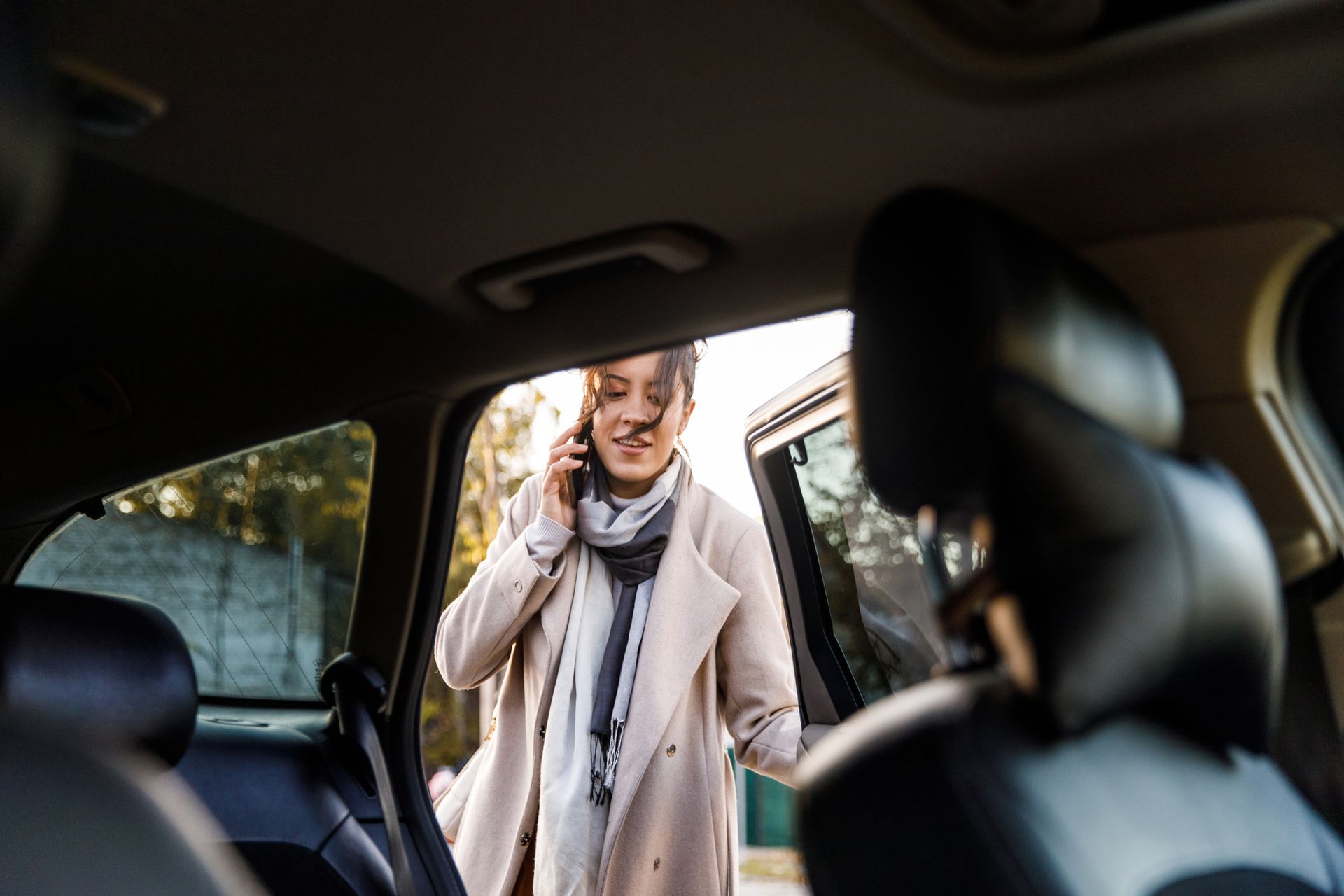 A woman is talking on a cell phone while getting out of a car. A woman is talking on a cell phone while getting out of a car.