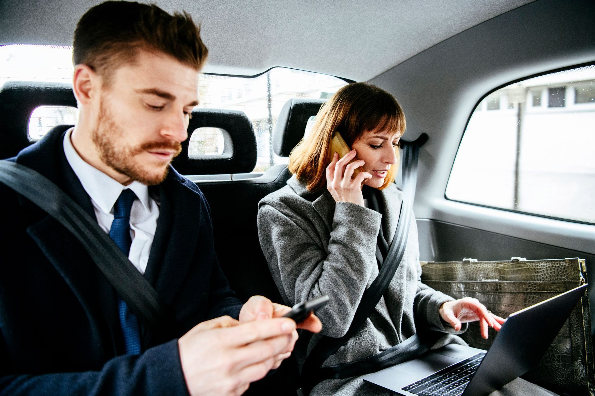 A man and a woman are sitting in the back seat of a car. A man and a woman are sitting in the back seat of a car.