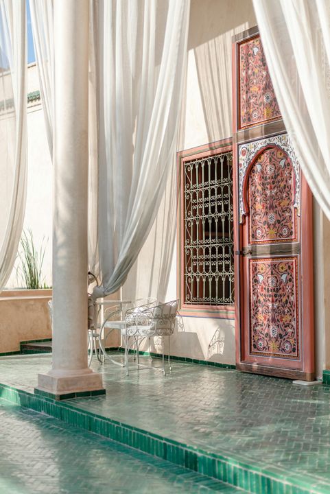 A door with a floral design is behind a white curtain.