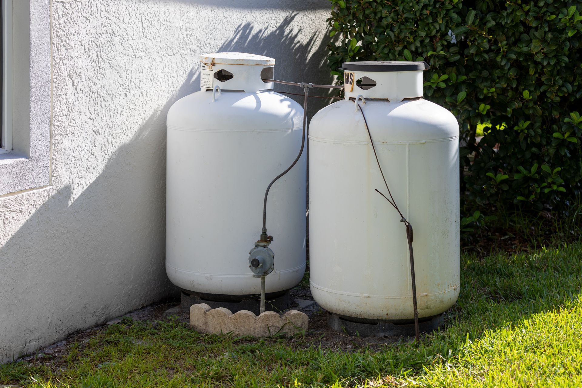 Two outdoor propane tanks connected to a home gas line, used for residential energy supply.
