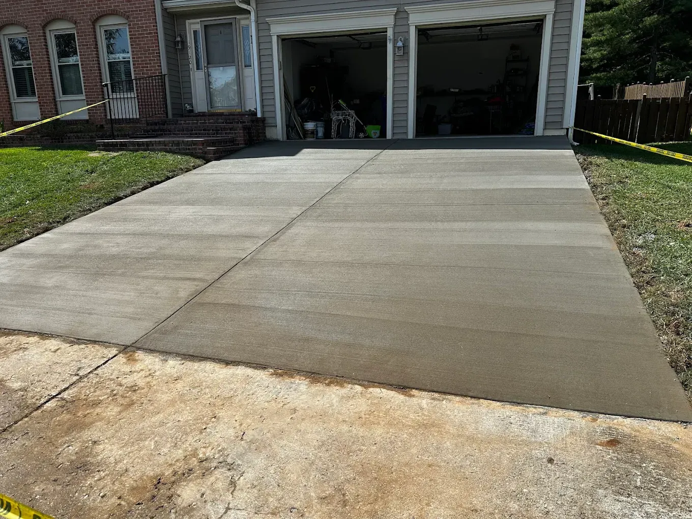 Fresh concrete driveway leading to a house with two open garage bays
