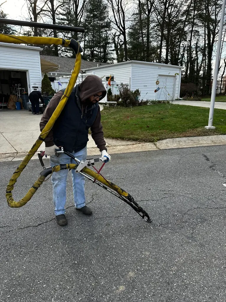 Person holding a yellow hose nozzle beside a white utility truck in a parking lot
