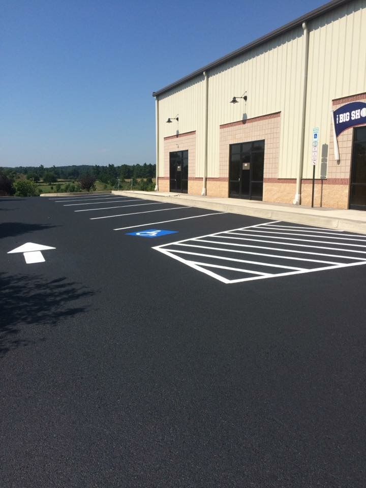Accessible parking spaces and a storefront parking lot with fresh black pavement and white markings.